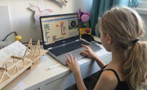 a girl using Scratch on a laptop at home